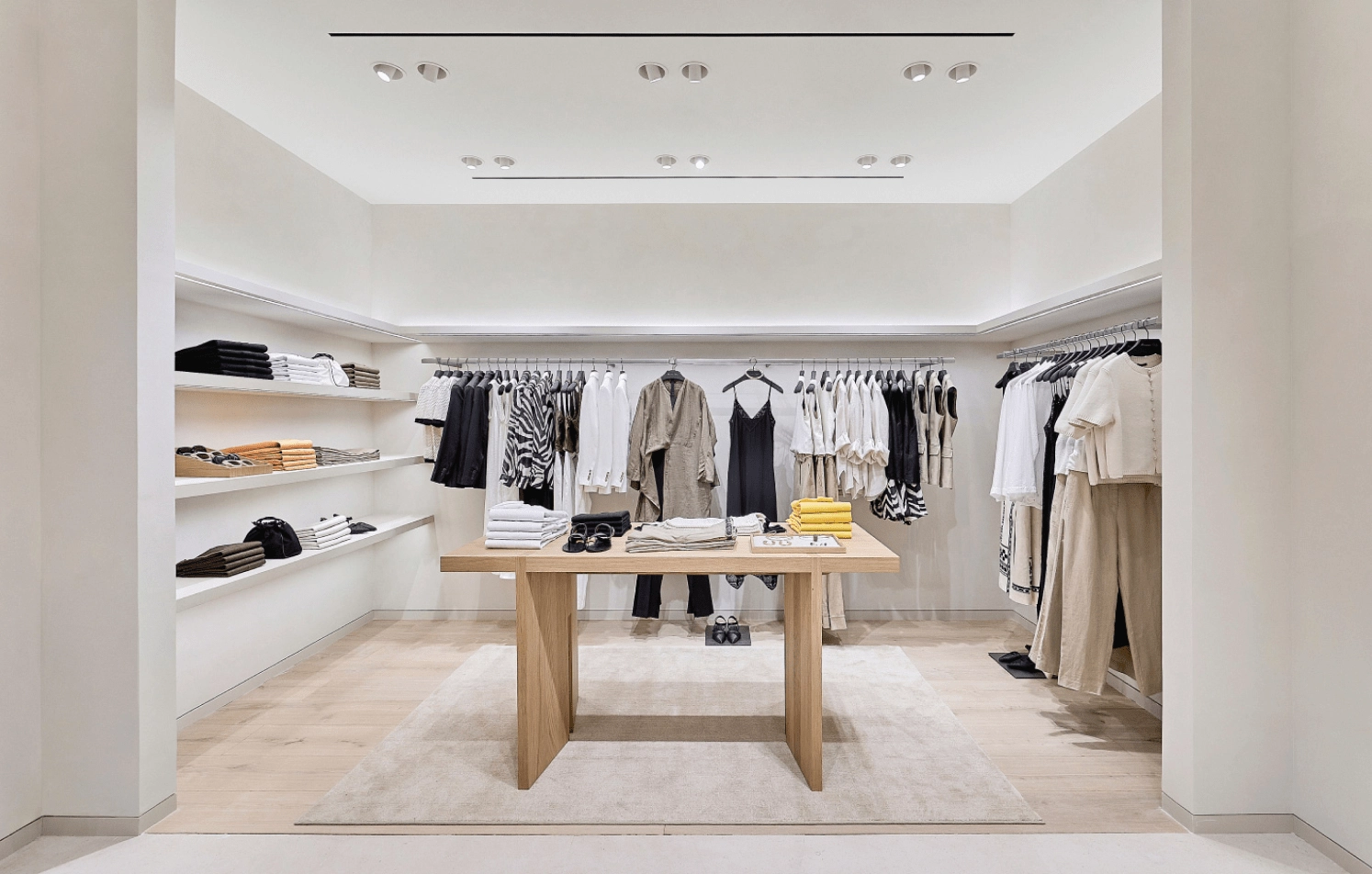 Minimalist clothing store interior with neutral tones and neatly arranged garments on racks and shelves