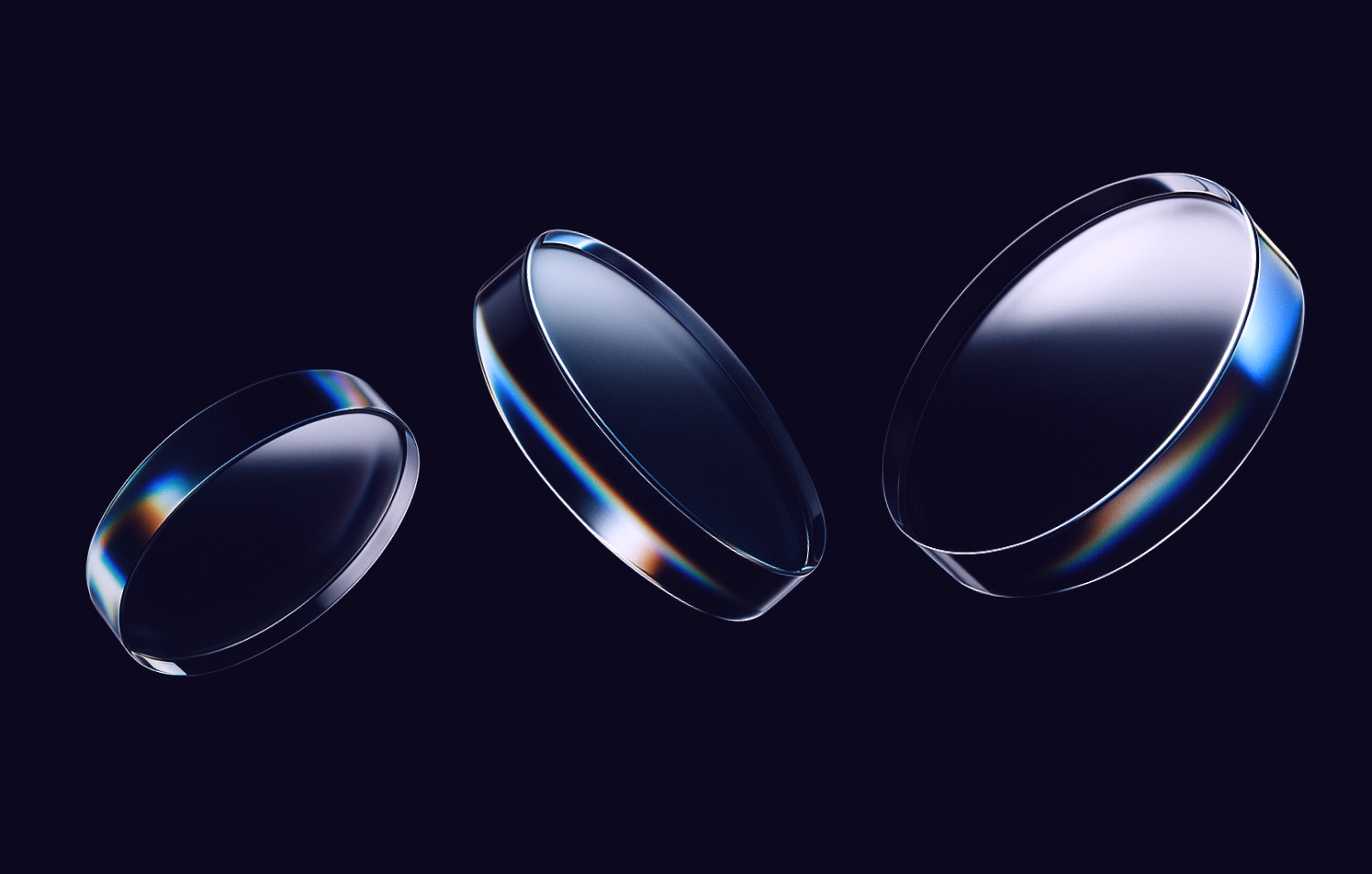 Three glass lenses with rainbow reflections on a dark background